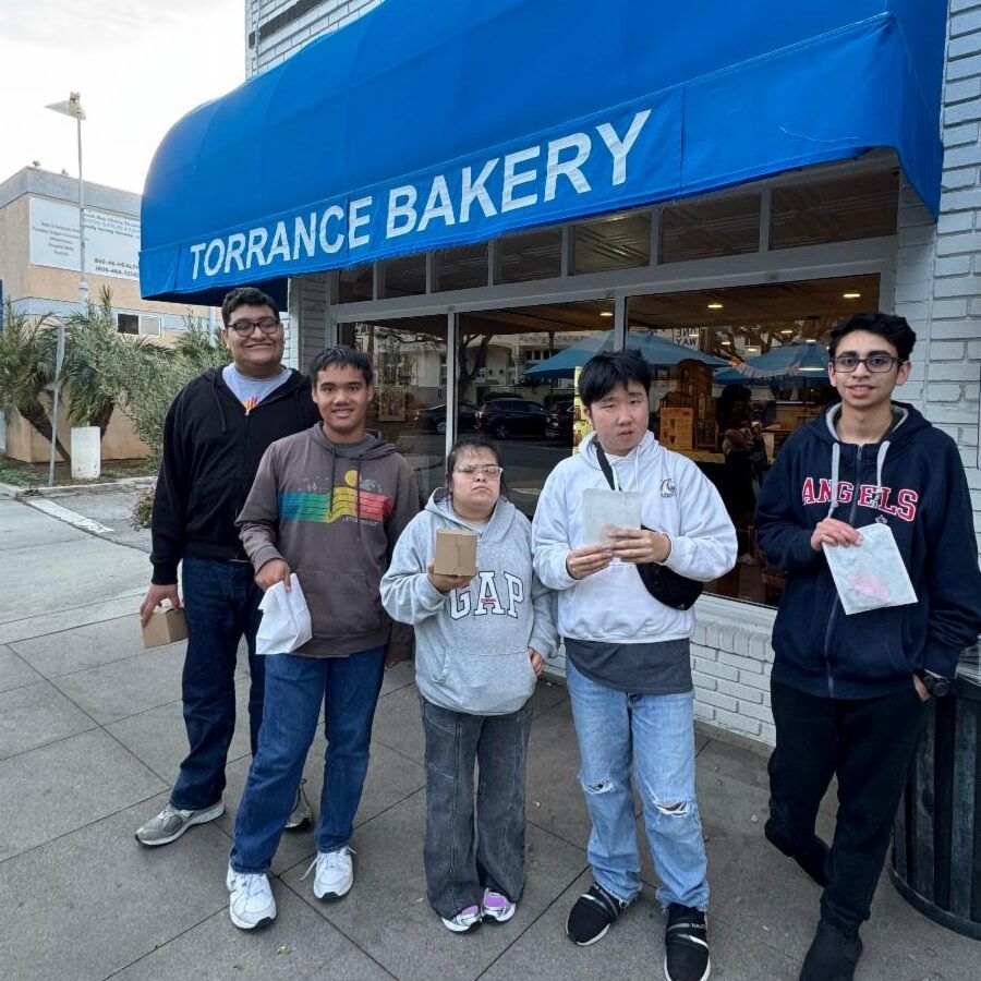 A group of five teens from the My Place program stand outside Torrance Bakery, holding small bakery boxes and handmade Valentine’s cards after a field trip focused on giving to others.